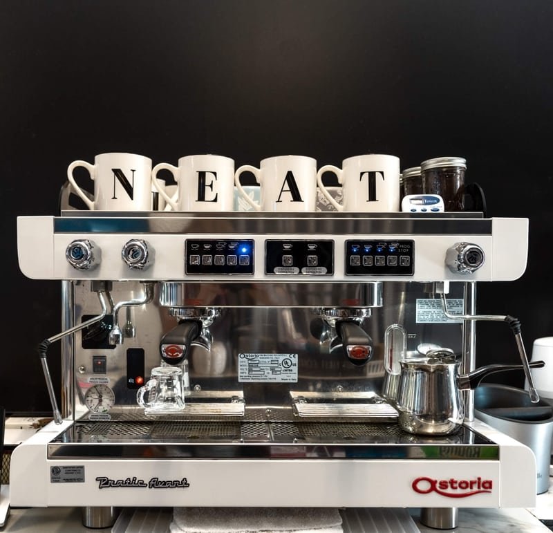 The NEAT Coffee Bar espresso machine with branded NEAT mugs lined up on top